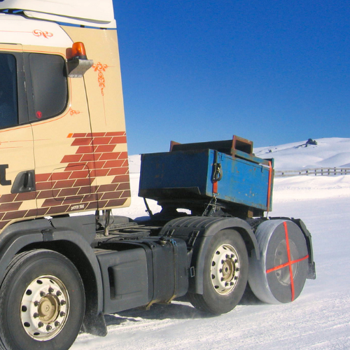 Chaussette de pneu AutoSock montée sur roue de camion, conduite sur neige dans un paysage hivernal