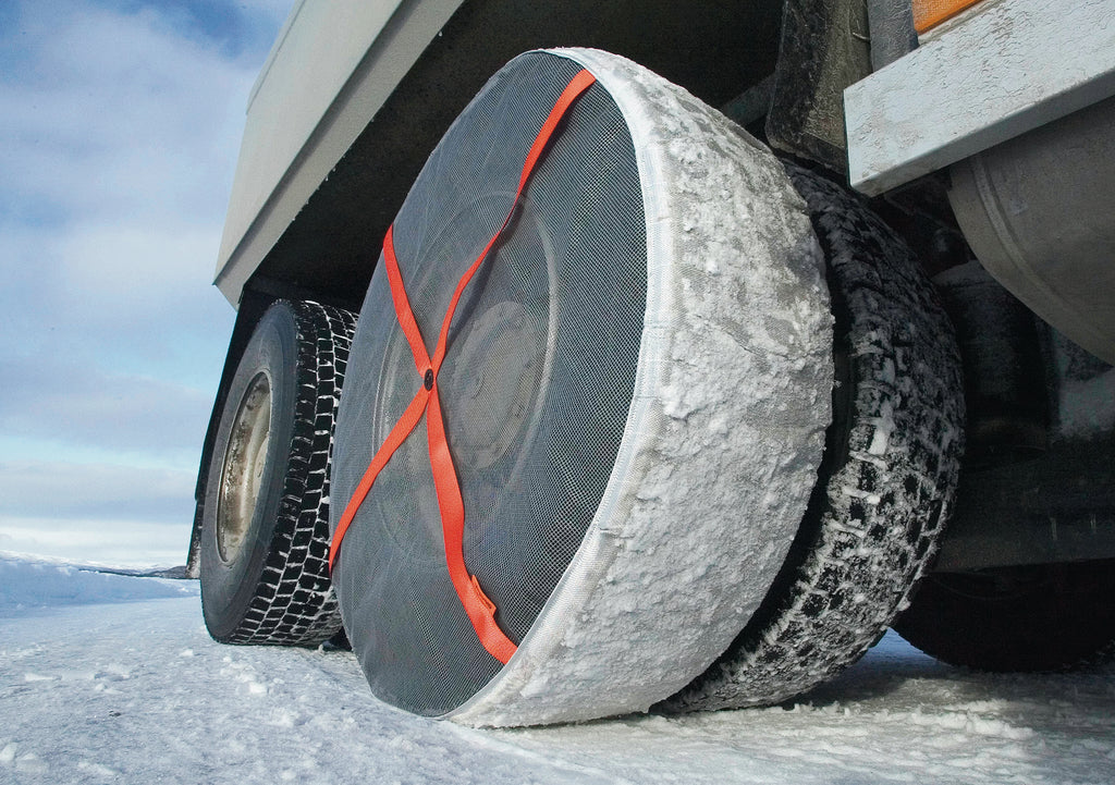 Gros camion avec chaussettes à neige AutoSock montées sur les roues arrière, debout sur la neige et la glace