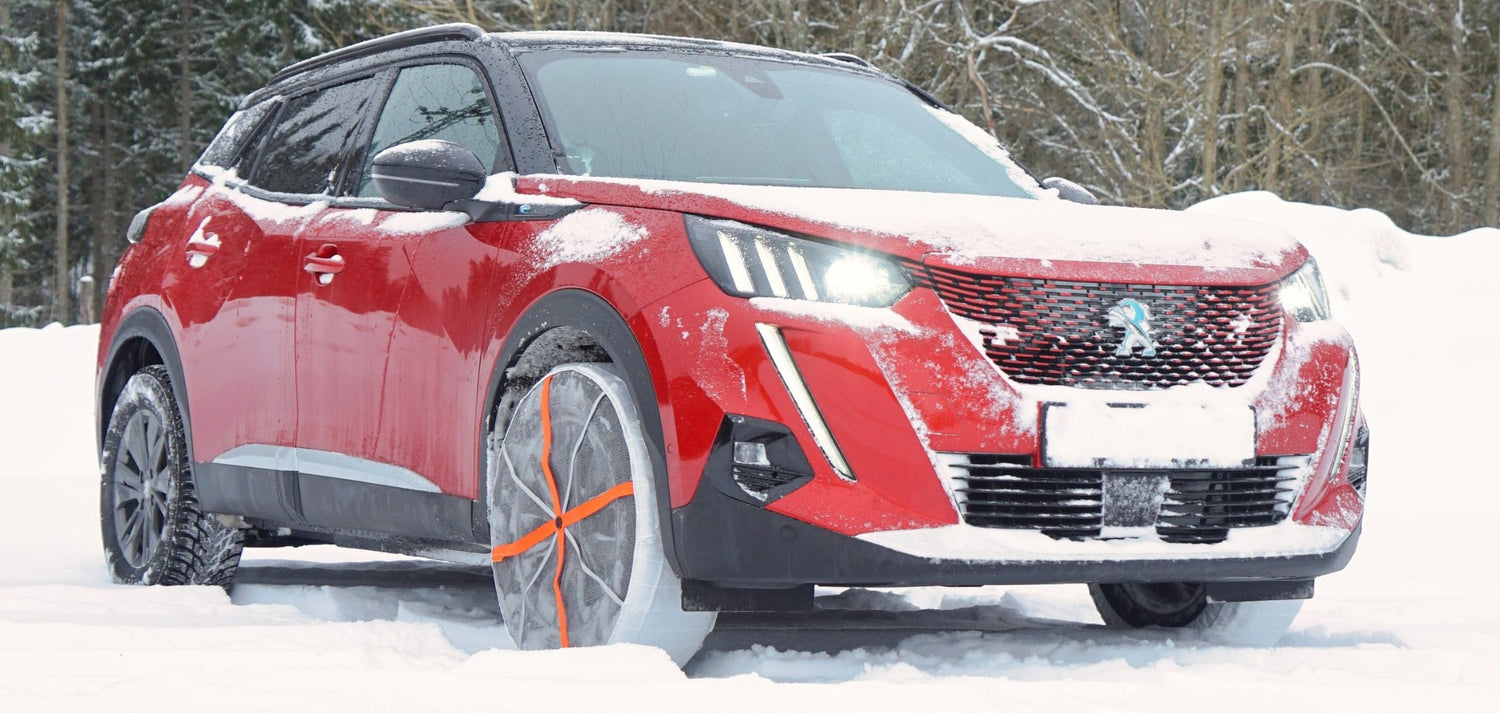 Chaussettes à neige montées sur les pneus avant d'un SUV Peugeot, debout sur la neige