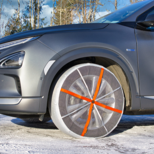 Vue latérale d'une voiture avec des chaussettes à neige AutoSock montées sur les roues avant