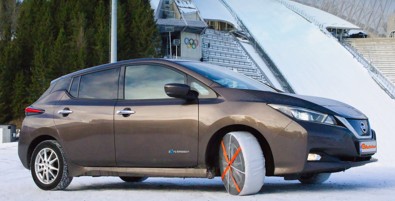 AutoSock entièrement monté sur une voiture de tourisme, debout devant une arène de saut à ski